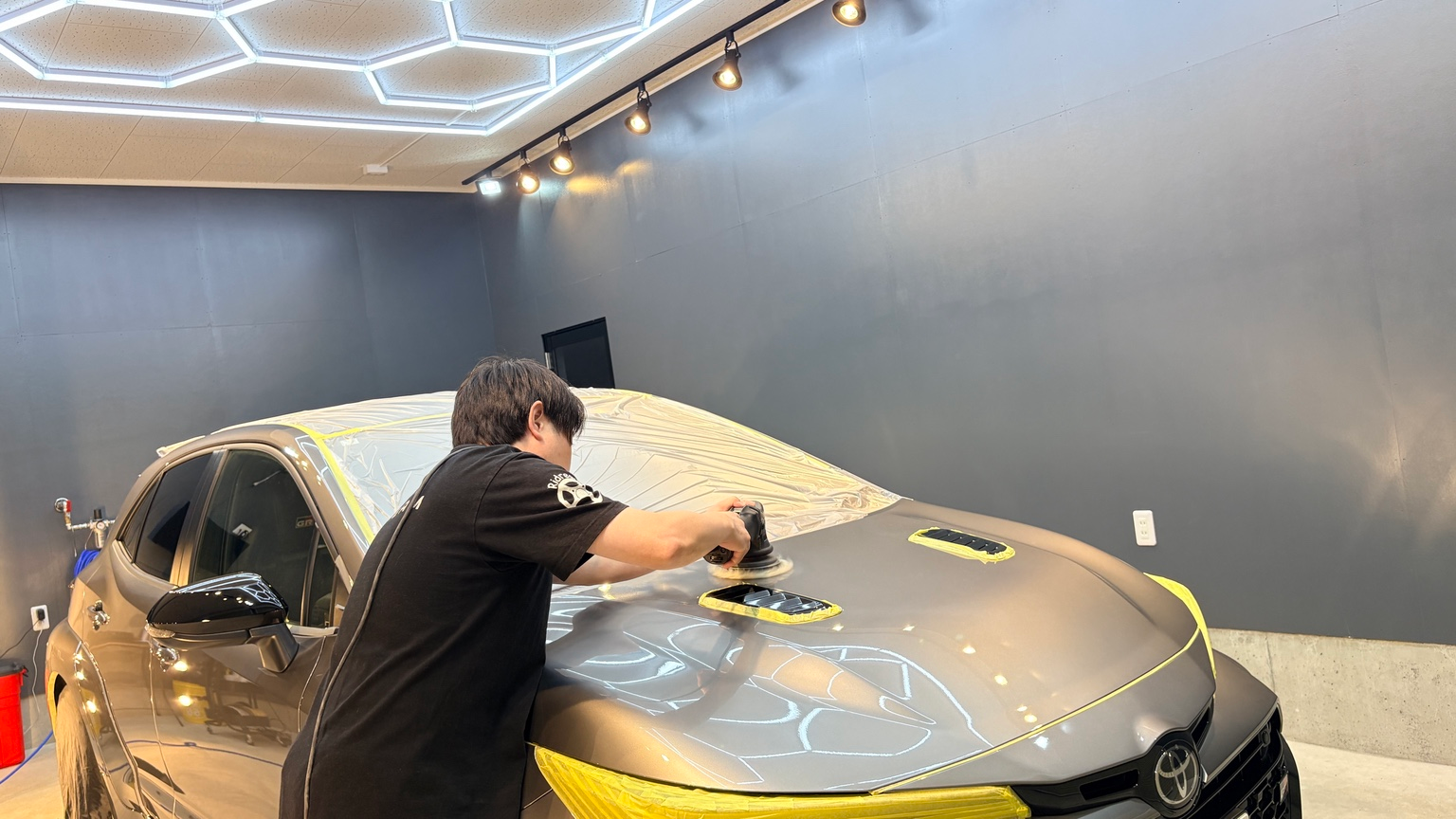 Ridreamの完全屋内の施工スペースでボンネットを研磨する作業風景